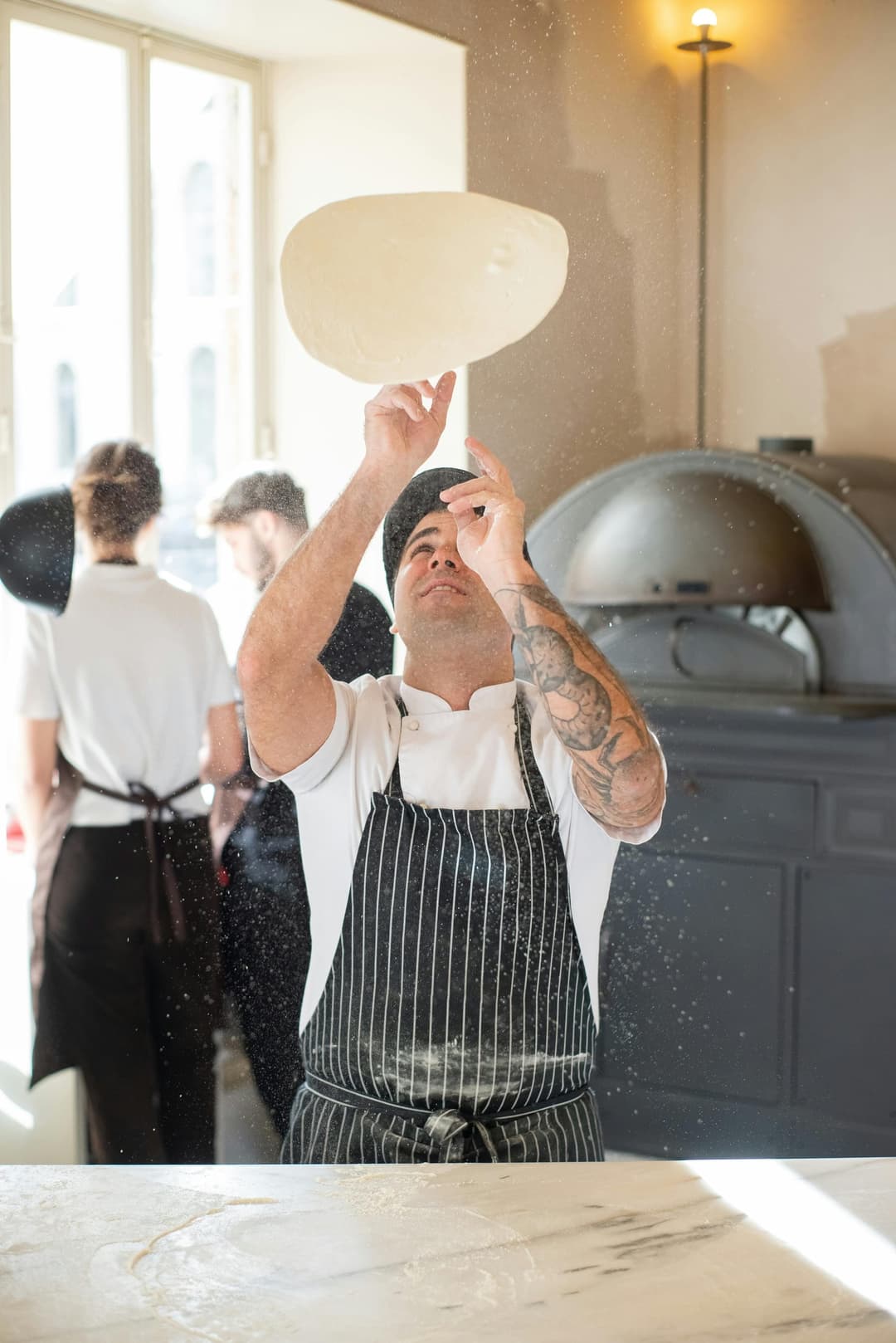Pizzeria chef tossing pizza dough in the kitchen